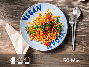 Pasta Bolognese vegan serviert auf einem blauen Teller. 