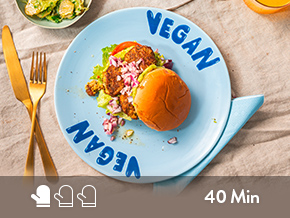 Veganer Burger auf Teller mit Besteck.