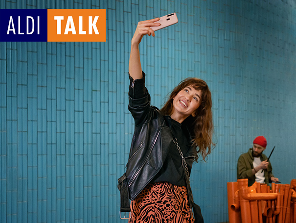 ALDI TALK. Frau hält Handy in der Hand und macht ein Selfie von sich.
