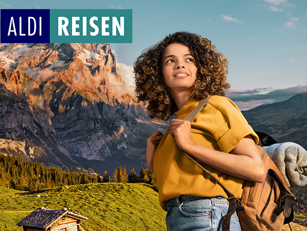 ALDI REISEN. Frau mit Rucksack auf dem Rücken in den Bergen.